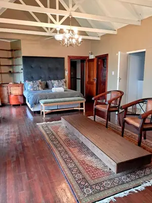 a living room with a bed and a table and chairs at Pavetta Country House in Magoebaskloof