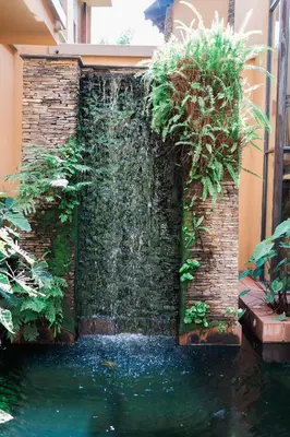 a retaining wall with a waterfall in a garden at Tayfin Royale Hotel & Conference Centre in Centurion