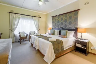 a bedroom with two beds and a large window at Porcupine Ridge Guest House in Sabie