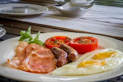 a plate of breakfast food with eggs sausage and tomatoes at Porcupine Ridge Guest House in Sabie