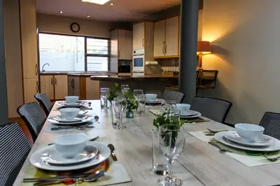 a dining room table with plates and glasses on it at Polo Guest House in Polokwane