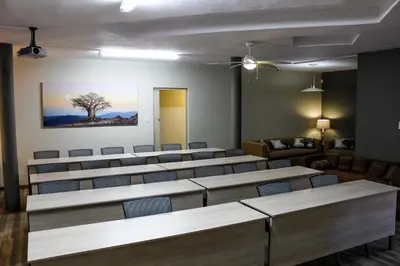 a room with tables and chairs and a tree on the wall at Polo Guest House in Polokwane