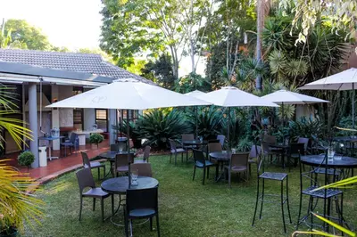 an outdoor restaurant with tables and chairs and umbrellas at Polo Guest House in Polokwane