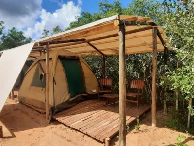 a tent with a deck and a table and chairs at Shik Shack Backpackers in Guernsey Nature Reserve