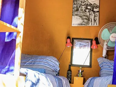 a bedroom with two beds and a lamp and a window at Shik Shack Backpackers in Guernsey Nature Reserve