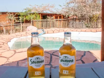 two bottles of beer sitting on a table next to a swimming pool at Shik Shack Backpackers in Guernsey Nature Reserve