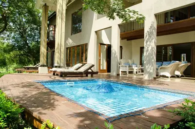 a swimming pool in front of a house at Villa Rostrata-on-Lake in Hazyview