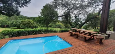 a wooden deck with a picnic table and a swimming pool at Villa Rostrata-on-Lake in Hazyview