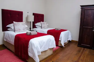 a bedroom with two beds with red and white sheets at Villa Rostrata-on-Lake in Hazyview
