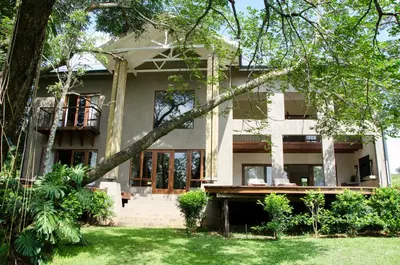 a white building with trees in front of it at Villa Rostrata-on-Lake in Hazyview