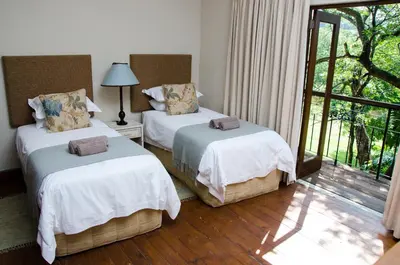 two beds in a room with a window at Villa Rostrata-on-Lake in Hazyview