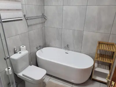 a bathroom with a tub and a toilet and a sink at Lamor Guest House in Middelburg