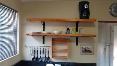 a kitchen with wooden shelves and utensils on the wall at 298 on 34th in Pretoria