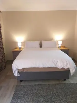 a bedroom with a bed with two lamps on two tables at 298 on 34th in Pretoria