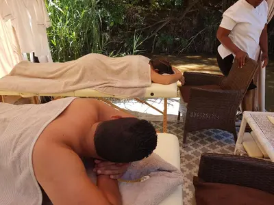 a man laying on a bed with his head on a table at Iris Retreat & Island Day Spa in Hartbeespoort
