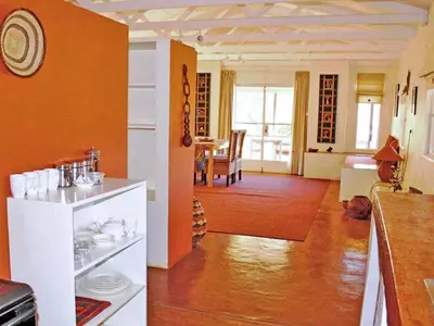 a kitchen and living room with an orange wall at Madi a Thavha Mountain Lodge in Louis Trichardt