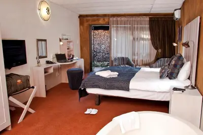 a hotel room with a large bed and a desk at African Rock Hotel & Spa, a 