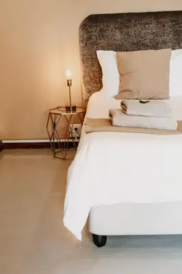a bedroom with a white bed and a side table at Lighthouse Guesthouse & Cafe in Groblersdal