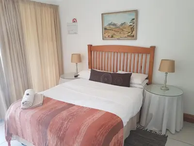 a bedroom with a bed and two tables with lamps at Homestead Lake Cottage in Benoni