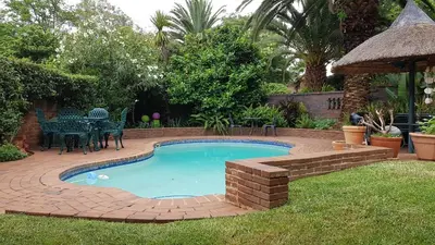 a small swimming pool in a yard with a brick patio at Homestead Lake Cottage in Benoni