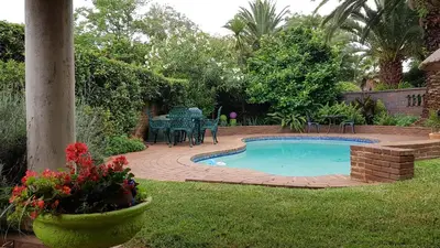 a swimming pool in a yard with a table and chairs at Homestead Lake Cottage in Benoni