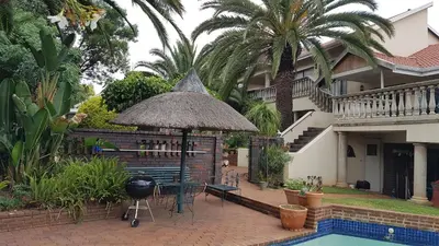 a patio with a grill and an umbrella next to a house at Homestead Lake Cottage in Benoni