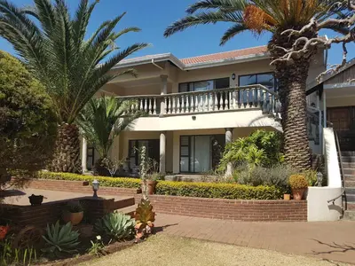 a house with palm trees in front of it at Homestead Lake Cottage in Benoni