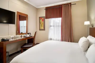 a hotel room with a bed and a desk at Protea Hotel by Marriott Pretoria Hatfield in Pretoria