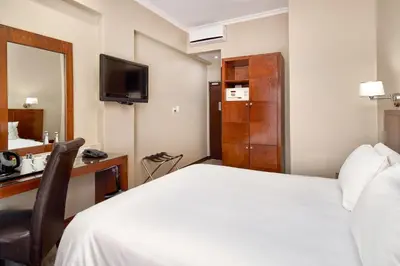 a hotel room with a bed and a desk and a television at Protea Hotel by Marriott Pretoria Hatfield in Pretoria