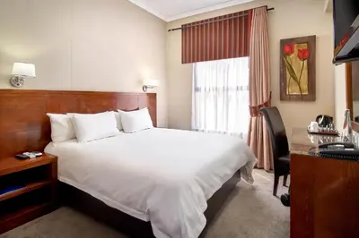 a hotel room with a bed and a desk and a window at Protea Hotel by Marriott Pretoria Hatfield in Pretoria
