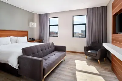 a hotel room with a bed and a couch at Protea Hotel by Marriott Pretoria Hatfield in Pretoria