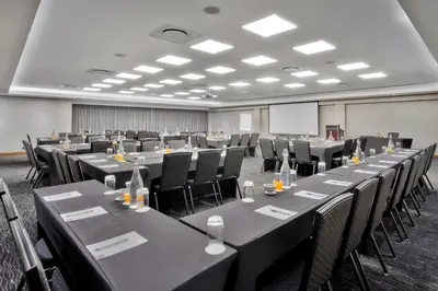 a conference room with tables and chairs and a screen at Protea Hotel by Marriott Pretoria Hatfield in Pretoria