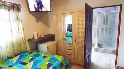 a bedroom with a bed and a refrigerator and a window at Sir Pinto Guesthouse in Witbank
