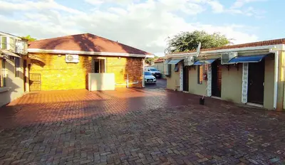 a brick parking lot next to a building at Sir Pinto Guesthouse in Witbank