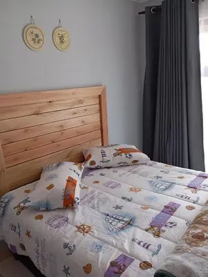 a bed with a comforter and pillows on it at Minco Guesthouse in Kempton Park