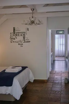 a bedroom with a bed and a chandelier on the wall at Be Our Guest Self Catering in Nelspruit
