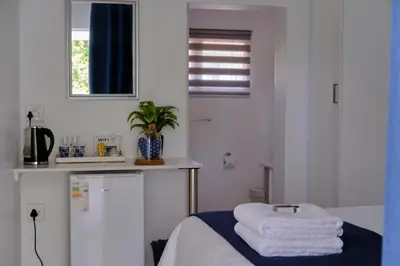 a white room with a bed with towels on it at Be Our Guest Self Catering in Nelspruit