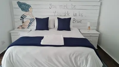 a bedroom with a large white bed with blue pillows at Be Our Guest Self Catering in Nelspruit