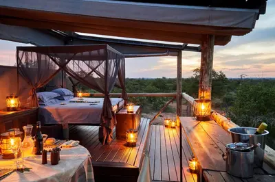 a room with a bed on a deck with lights at Motswari Private Game Reserve by NEWMARK in Timbavati Game Reserve