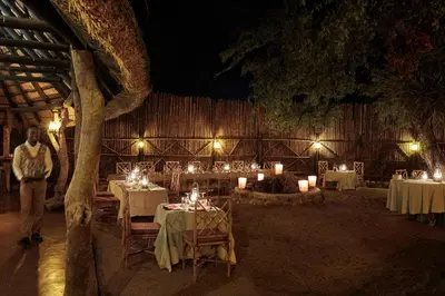 a man standing in front of a restaurant with tables with candles at Motswari Private Game Reserve by NEWMARK in Timbavati Game Reserve