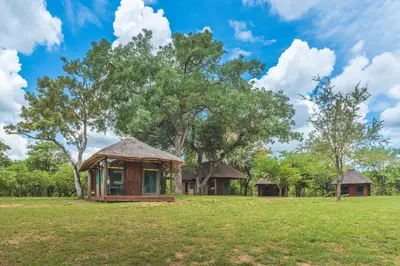 a small house in a field with trees at Shindzela Tented Camp in Timbavati Game Reserve