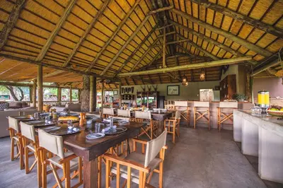 a restaurant with a large wooden table and chairs at Shindzela Tented Camp in Timbavati Game Reserve