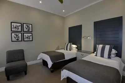 a hotel room with two beds and a chair at Dunkeld Country & Equestrian Estate in Dullstroom