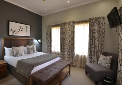 a bedroom with a bed and a chair and a television at Dunkeld Country & Equestrian Estate in Dullstroom