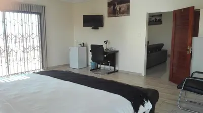 a bedroom with a bed and a desk and a television at Estoby Executive guest house in Witbank