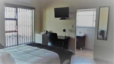 a bedroom with a bed and a desk and a computer at Estoby Executive guest house in Witbank
