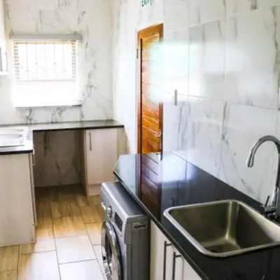 a kitchen with a sink and a washing machine at Estoby Executive guest house in Witbank