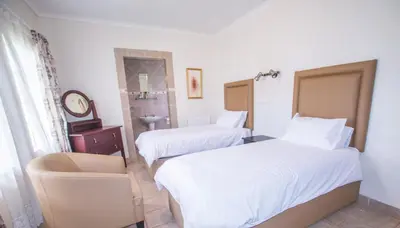 a hotel room with two beds and a chair at Hoyohoyo Machadostud Lodge in Helvetia Noord