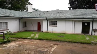 a white building with a red door and a yard at Hoyohoyo Machadostud Lodge in Helvetia Noord