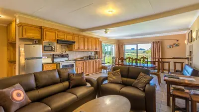 a living room with two leather couches and a kitchen at Hoyohoyo Machadostud Lodge in Helvetia Noord